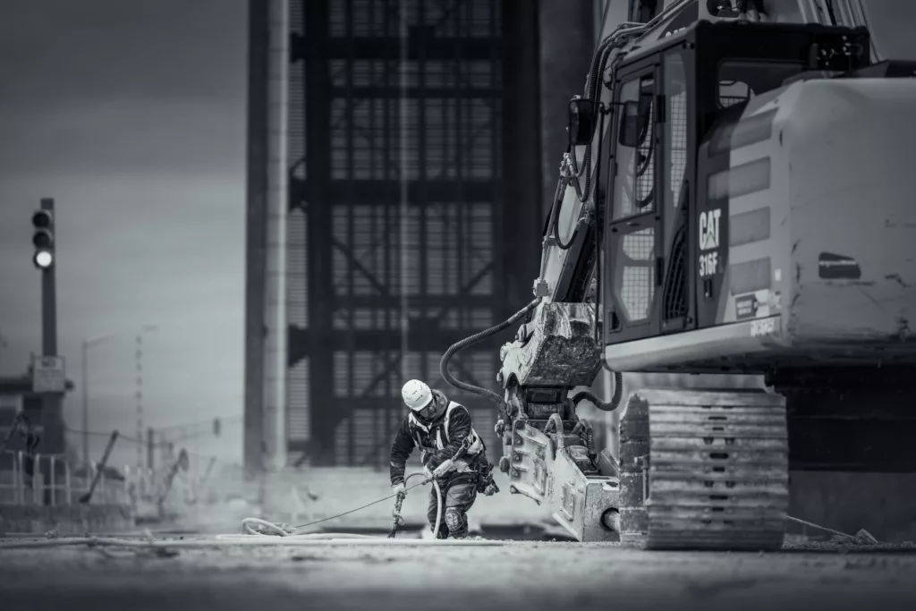 man and excavator photo during construction of a bridge